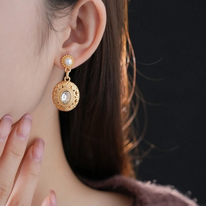 Close-up of vintage gold pearl earrings with a central crystal on a model's ear
