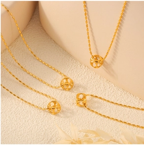 Macro detail of the gold-plated hollow cube pendant on a delicate beaded chain necklace
