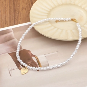 Elegant pearl necklace with a gold heart-shaped pendant on a minimalist background