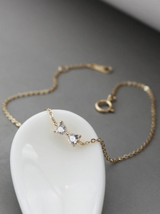 Detail of 14k gold plated S925 silver bracelet with heart-shaped zircon bow on a spoon