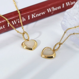 Elegant gold heart pendant necklace with white mother of pearl inlay on red background