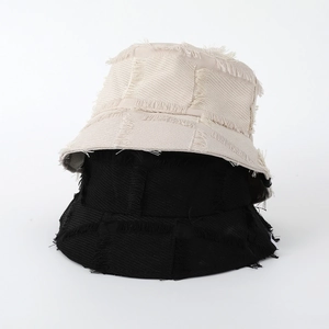 Close-up of beige and black bucket hats featuring unique raw edge fringe stitching details