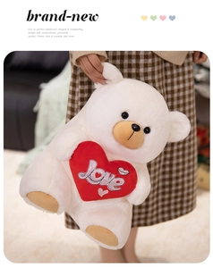 Detail of soft white teddy bear holding a red heart with Love embroidery and silver accents