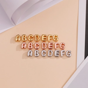 Detailed macro view of 18K gold and silver bubble letter charms for DIY jewelry making