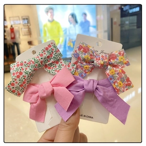 Close-up of floral and solid bow hair clips for girls on white card packaging