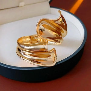 Detail of a wavy irregular gold metal cuff bracelet resting in a premium jewelry box