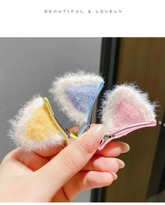 Detailed view of three plush cat ear hair clips in yellow, purple, and pink for kids