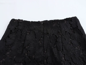 Dettaglio di una gonna corta in pizzo nero con cerniera nascosta e motivi floreali