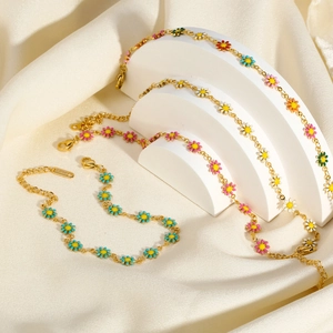 Three multi-colored enamel daisy bracelets on 18K gold-plated stainless steel chains