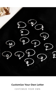 Macro detail of adjustable letter rings with micro-pave zircons on black velvet background