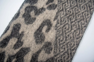Close-up of leopard and geometric pattern scarf with soft knit texture and fringe edge