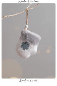 Close-up of plush glove Christmas ornament with wooden snowflake on a tree branch