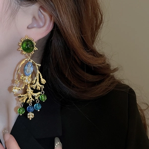 Gros plan de boucles d'oreilles baroques corail avec pierres vertes et perles de verre