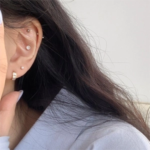 Close-up of 925 sterling silver gold earrings with zircon and pearls on ear