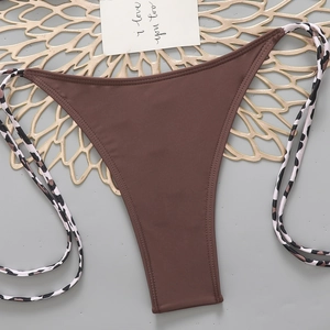 Detail of dark brown bikini bottom featuring side leopard print tie straps on luxury mat