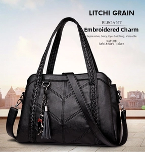 Detail of black litchi grain tote bag with woven handles and cat charm ornament