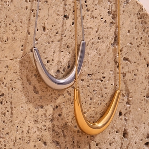 Detail of minimalist 18K gold and silver V-shaped pendants on fine snake chains