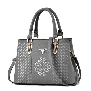 Close-up of silver floral embroidery and gold hardware on grey crossbody handbag