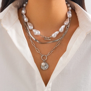 Detail of triple-layer silver necklace with baroque pearls, snake chain, and coin pendant
