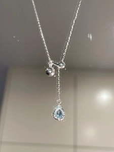 Macro detail of silver drop pendant necklace with light blue sapphire and adjustable chain