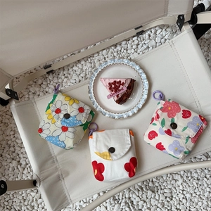 Floral mini storage bags for sanitary napkins displayed on a rustic outdoor chair
