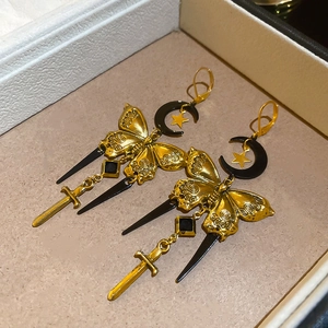 Détail de boucles d'oreilles papillon vintage avec breloques lune et épée
