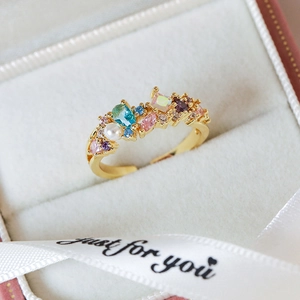 Macro view of adjustable gold ring with multi-color zircons and white pearl in a gift box