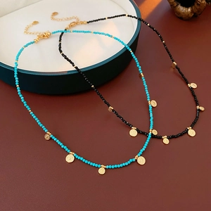 Détail de colliers ethniques avec perles bleues et noires et pendentifs disques dorés