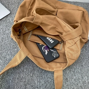 Large brown canvas tote bag interior view showing high capacity and zip pocket detail