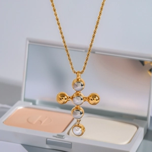 Collier croix dorée avec pendentif en pierre blanche et chaîne torsadée élégante