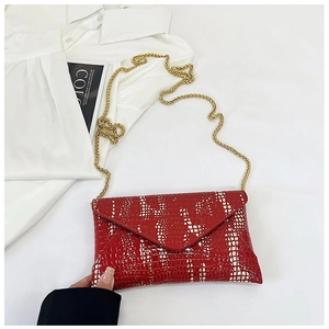 Detail of red envelope bag with faux snake texture and golden chain strap