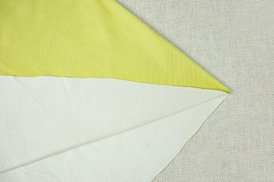 Macro detail of the yellow-green twill fabric and light grey satin back of the dress