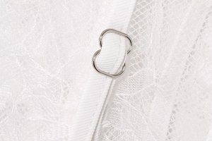 Macro detail of white lace fabric with premium metal adjustment ring on a strap
