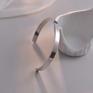 Bracelet jonc ouvert argenté en acier inoxydable sur fond artistique minimaliste