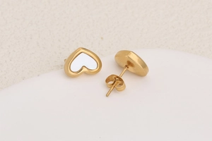 Detailed close-up of golden heart-shaped stud earrings with white pearl shell inlay