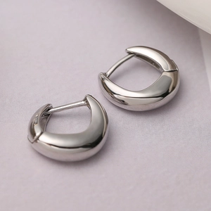 Macro shot of silver-plated hoop earrings with thick glossy finish on textured background