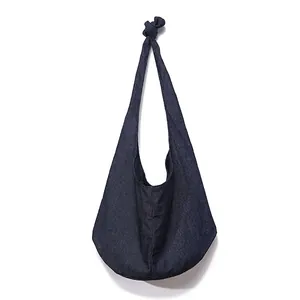 Detail of dark blue canvas crossbody bag showing a unique knotted strap design