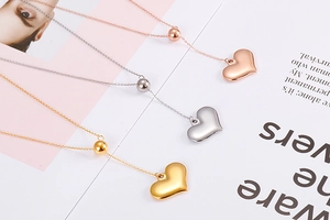 Polished heart pendant necklaces in rose gold, silver, and gold finishes on a magazine