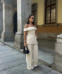 Detail of light beige off-shoulder top and wide-leg pants with textured fabric finish