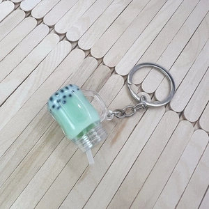 Macro view of mint green bubble tea keychain with pearls and silver chain on wood background