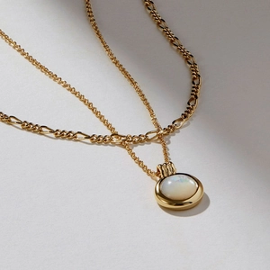 Detail of double-layer gold necklace with green aventurine and round opal pendant
