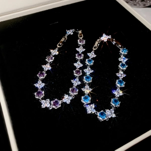 Detail of zircon flower bracelets in purple and blue crystal on black velvet