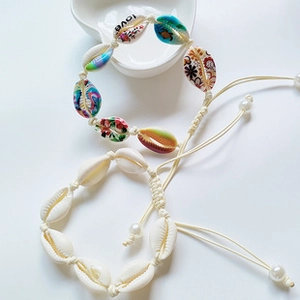 Detail of adjustable shell bead bracelets with LOVE print and pearl accents on white background