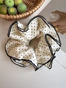 Detail of a black and white polka dot oversized scrunchie with delicate black stitched edges