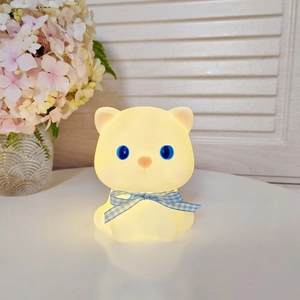 Cute glowing cat night light with blue checkered bow and soft warm yellow illumination