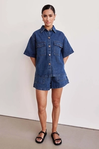Deep blue denim two-piece set featuring short-sleeved utility shirt and matching shorts