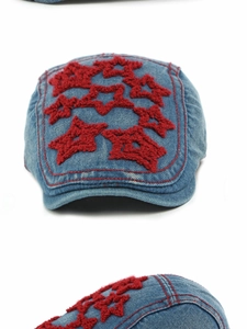 Detail of denim beret featuring red embroidered stars and contrast stitching details