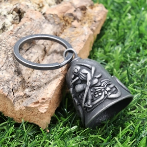 Detail of vintage silver grim reaper motorcycle bell pendant on natural tree bark
