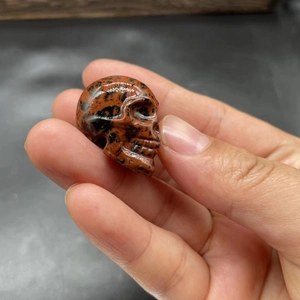 Macro shot of a 2.8cm hand-carved skull figurine made of polished red and black stone