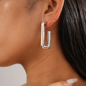 Close-up of a silver rectangular U-shaped geometric earring worn by a model